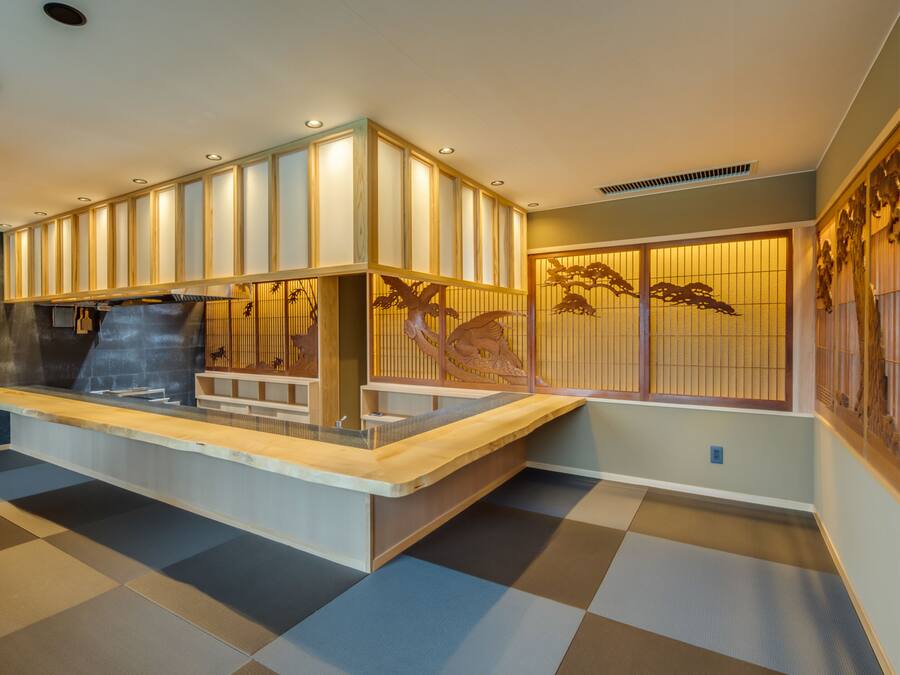 A traditional Japanese-style interior with tatami flooring, a reception desk, and shoji screens.