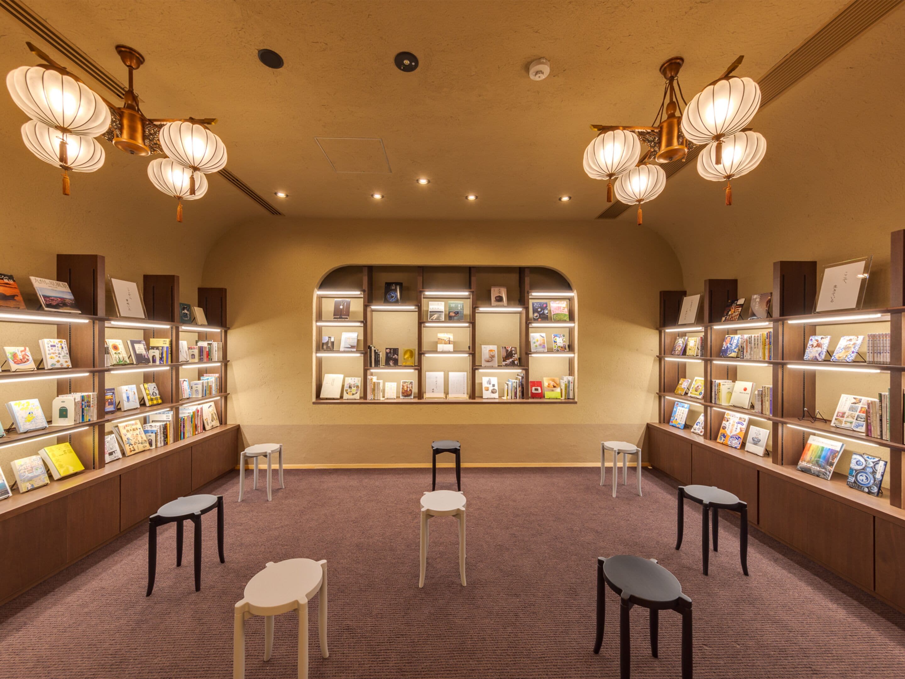 Una librería con estanterías llenas de libros y algunas sillas en el centro.