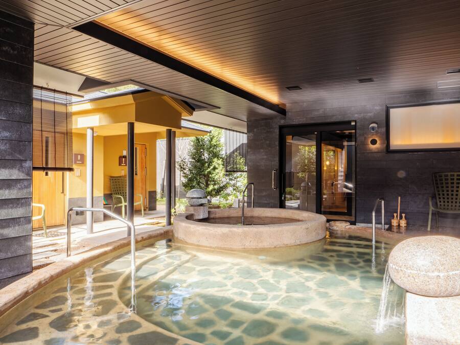 Un área de spa con aguas termales, techo de madera y zona de estar de piedra.