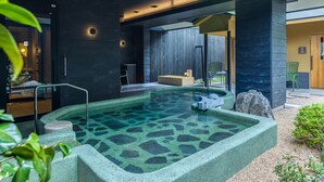 Un área de spa moderna con una piscina cristalina, escalones de piedra y una terraza de madera.