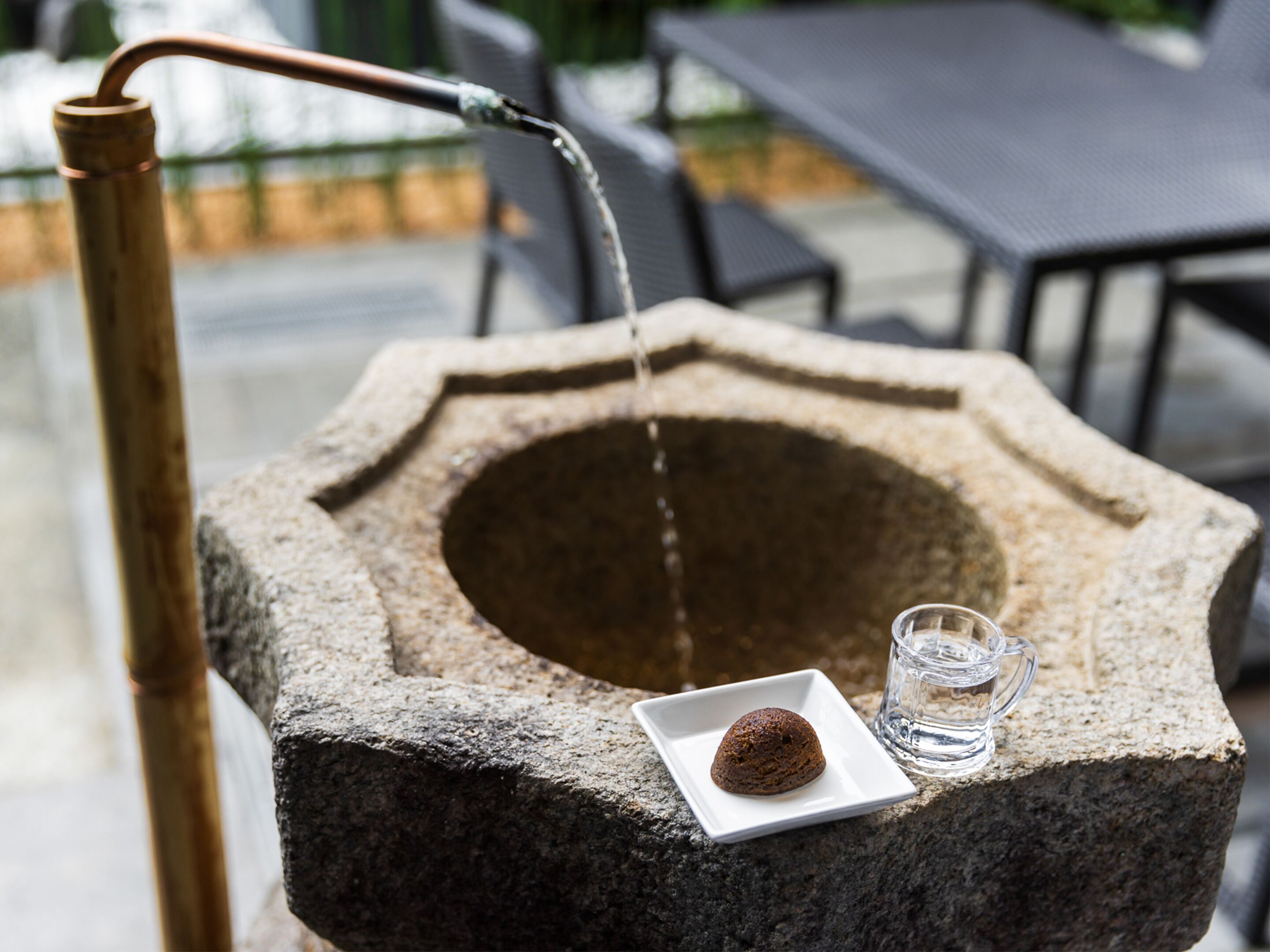 A stone well with a square plate and a glass of water.