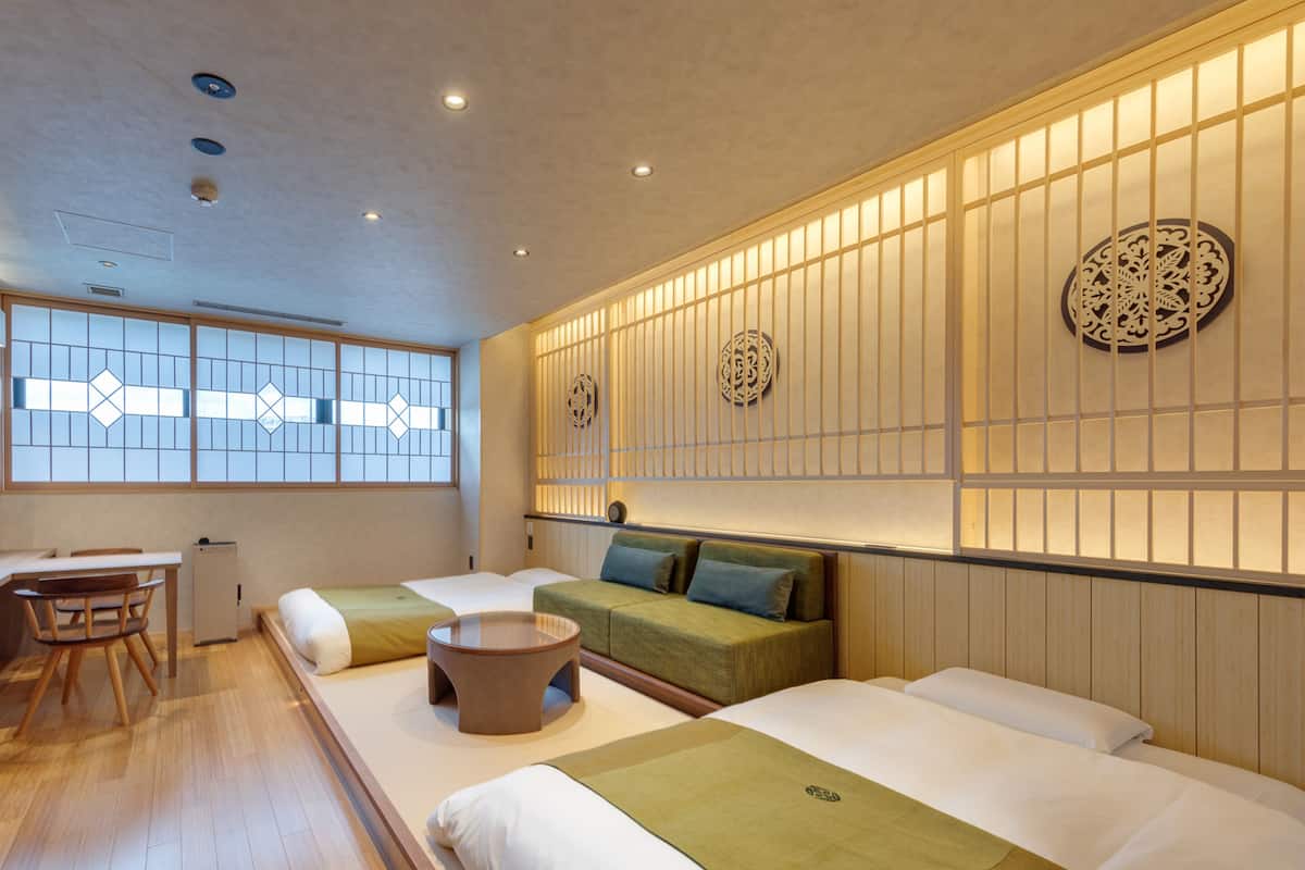 A traditional Japanese-style room with tatami flooring, a low table, and two tatami beds with cushions.