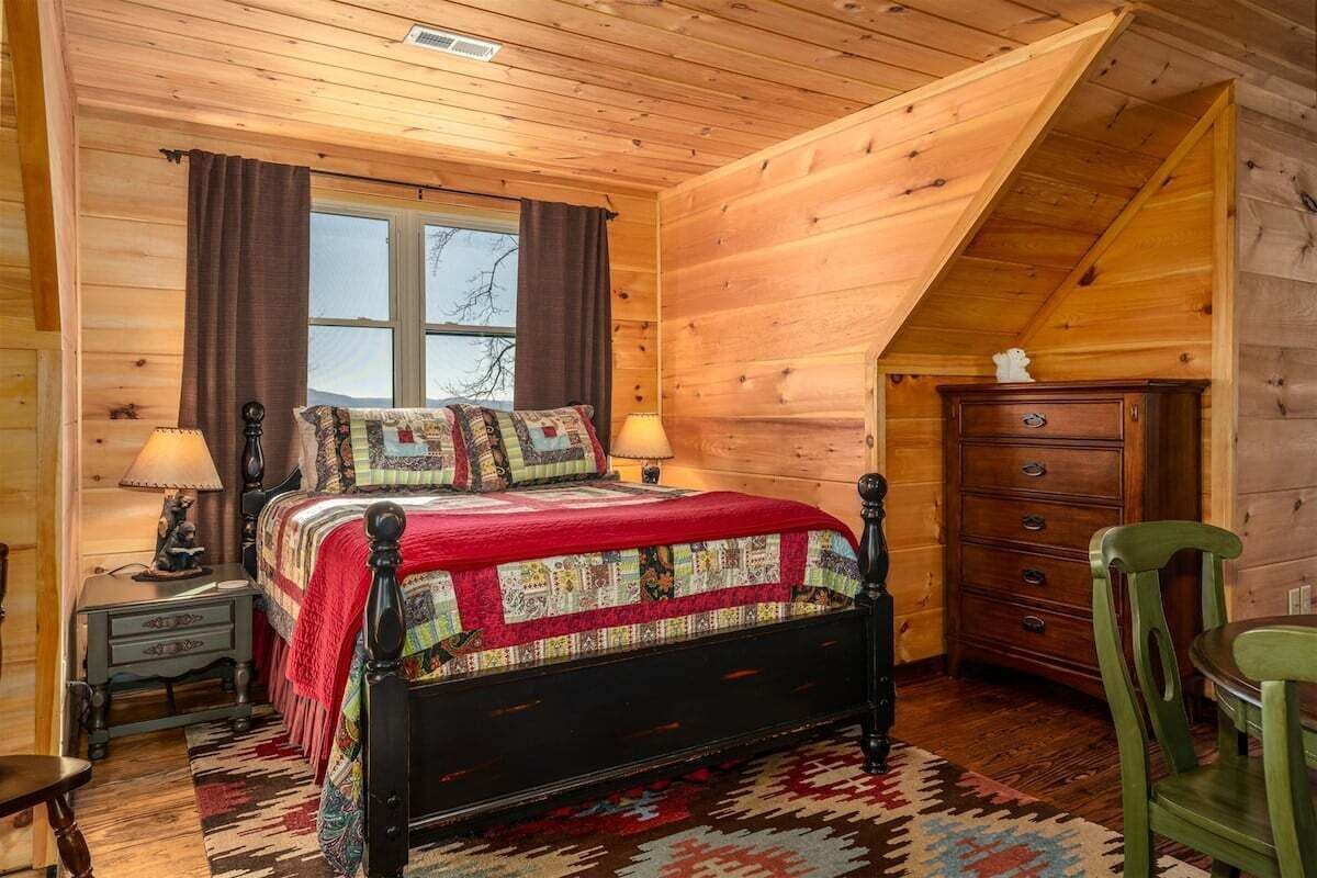 A wooden cabin bedroom with a bed, a dresser, and a chair.