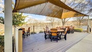 A covered outdoor patio with wooden deck, chairs, and a table. - Beautiful Branson Condo w/ Golf + Pool Access! (Branson)
