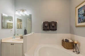 A bathroom with a bathtub, a sink, a mirror, and two towels hanging on the wall. - One of the  best wide lake and golf course views (Naples)