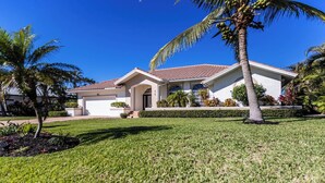 A two-story house with a tiled roof, a garage, and a well-maintained lawn with palm trees. - 3/2 Waterfront Pool/Spa Home (Marco Island)