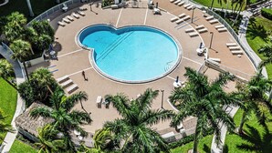 Ein kreisförmiger Pool mit Liegestühlen und Palmen.