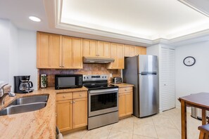 Enjoy cooking in this fully equipped kitchen with a sink, stove, microwave, and refrigerator, adjacent to a dining area with a table and chairs.