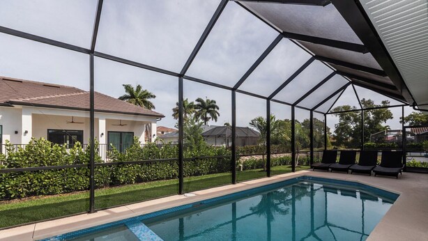 Piscina con vistas despejadas del entorno, incluyendo una casa y zonas verdes.