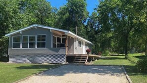 Einbungalow mit Veranda, Kiesweg und umzäunter Garten.