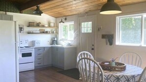 Eine Küche mit Holzschränken, einem Kühlschrank, einer Spüle und einem Esstisch mit Stühlen.