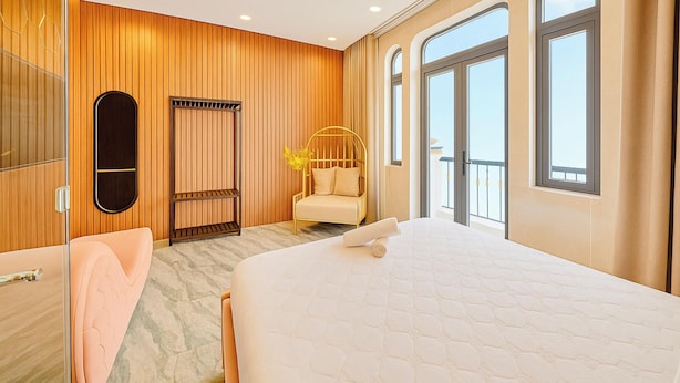 A hotel room with a large bed, a sitting area with a chair, a small table, and a view of the outside. - S79 T68 Hotel Go Vap (Ho Chi Minh City)