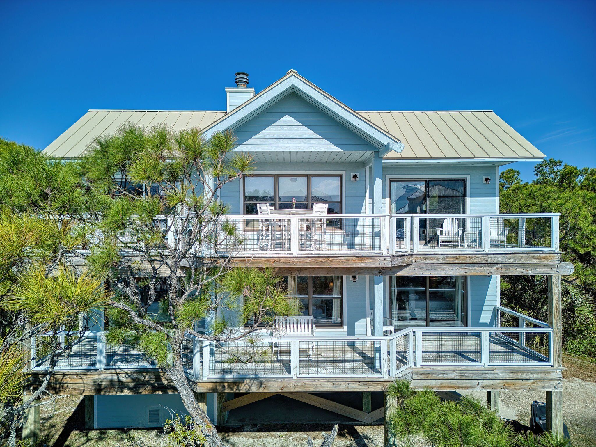 A two-story house with a balcony, large windows, and a wooden deck.