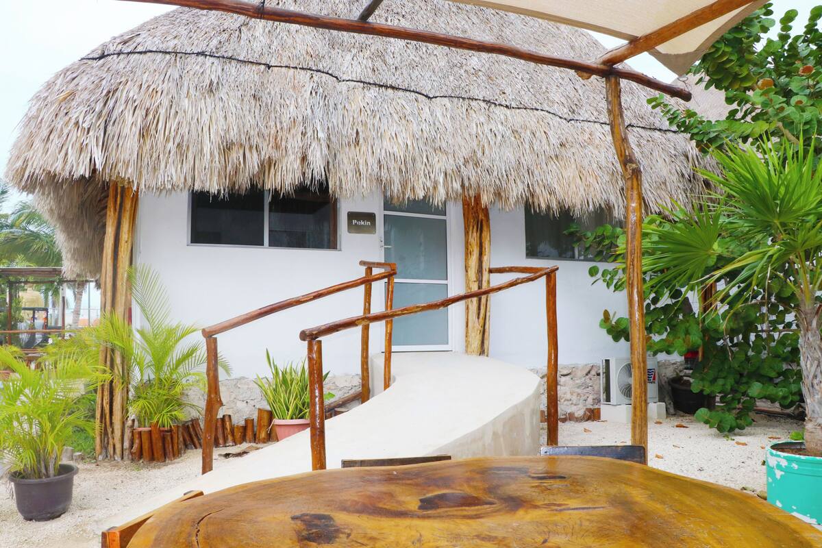 A thatched-roof building with a wooden staircase leading to a white door labeled "Pokin."