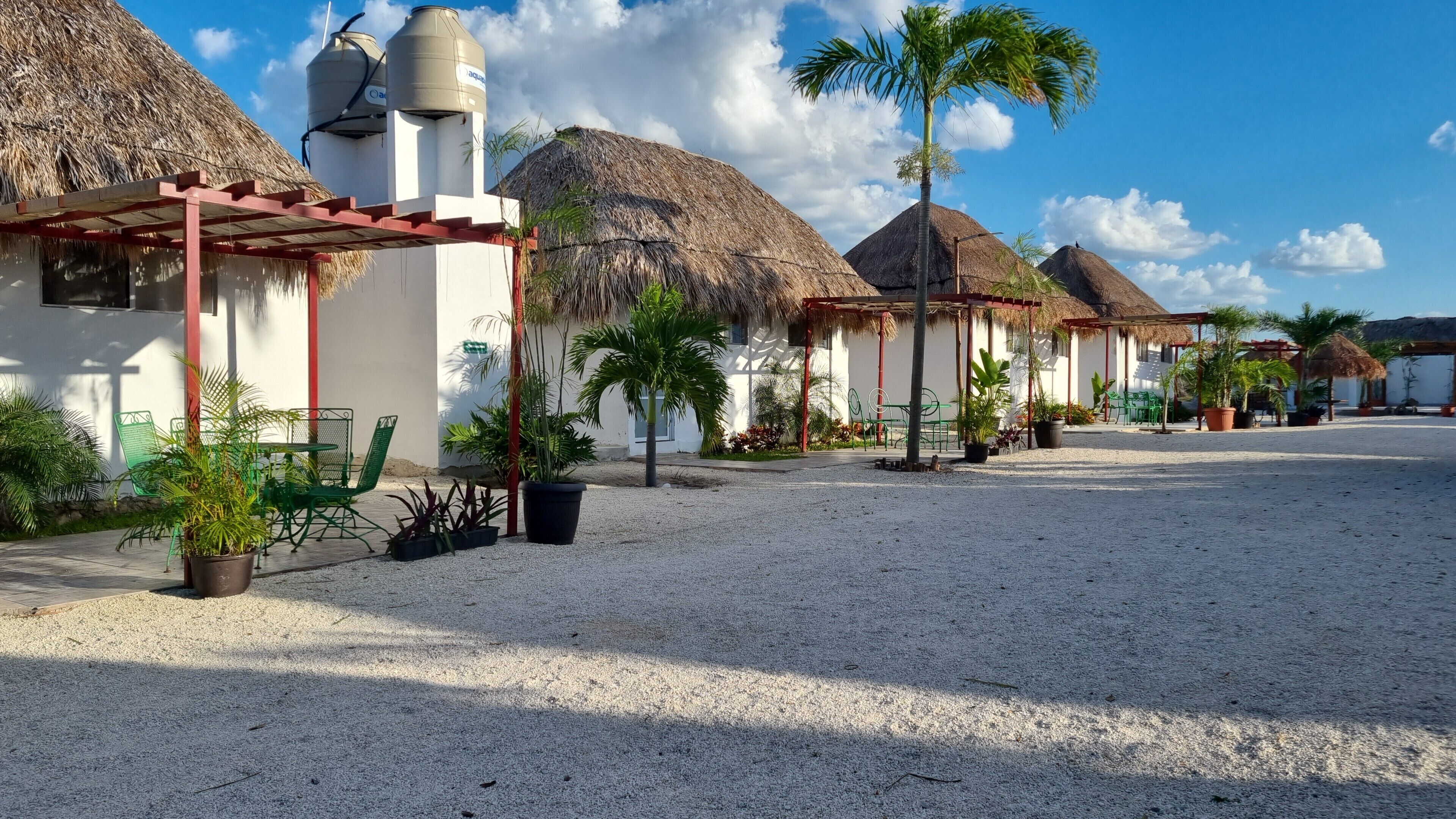 Un resort con construcciones de techo de paja, mobiliario exterior y plantas en macetas.