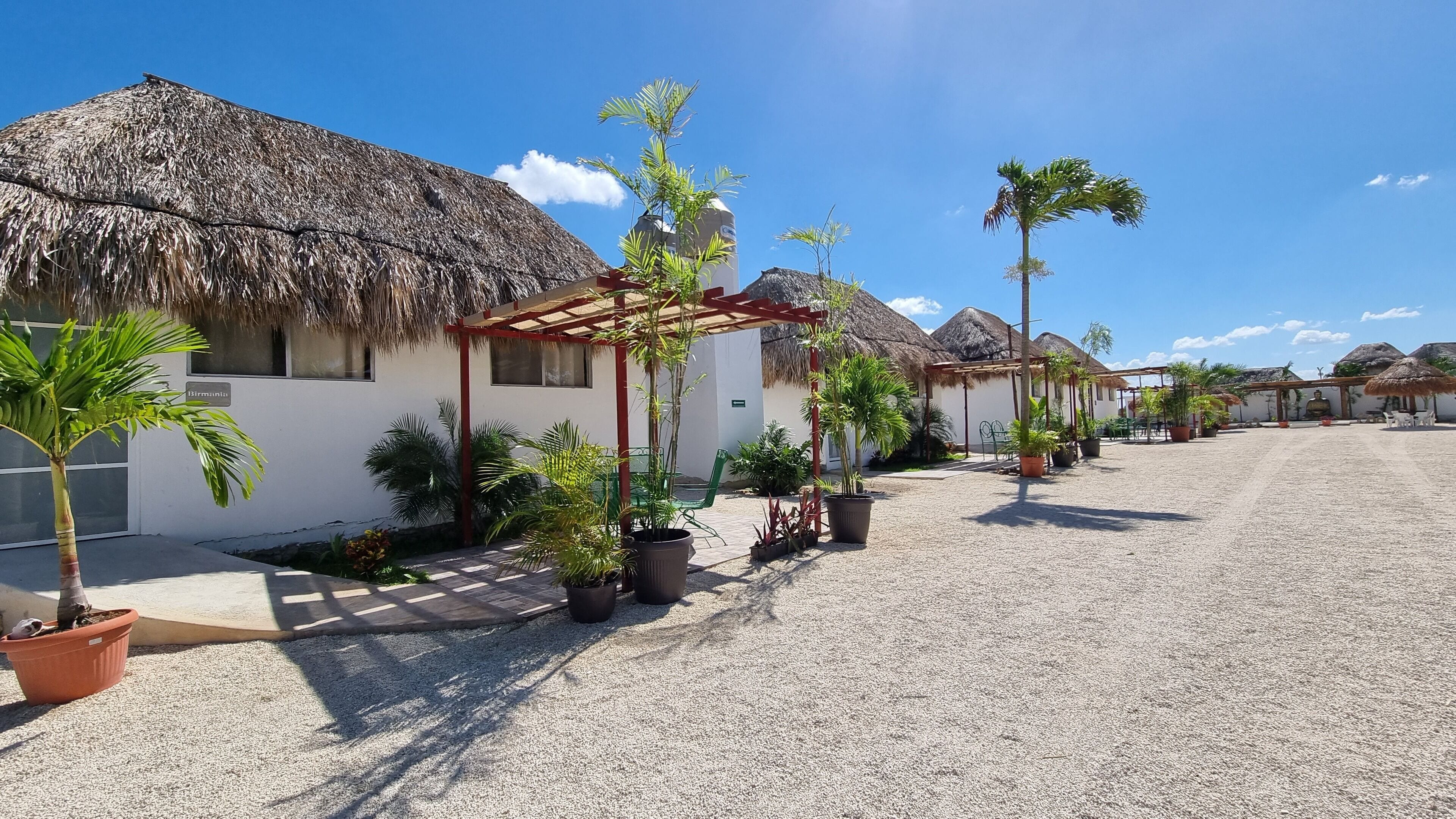 A resort with thatched-roof buildings, outdoor seating, and potted plants.