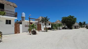 A coastal village with white buildings, palm trees, and thatched-roof structures.