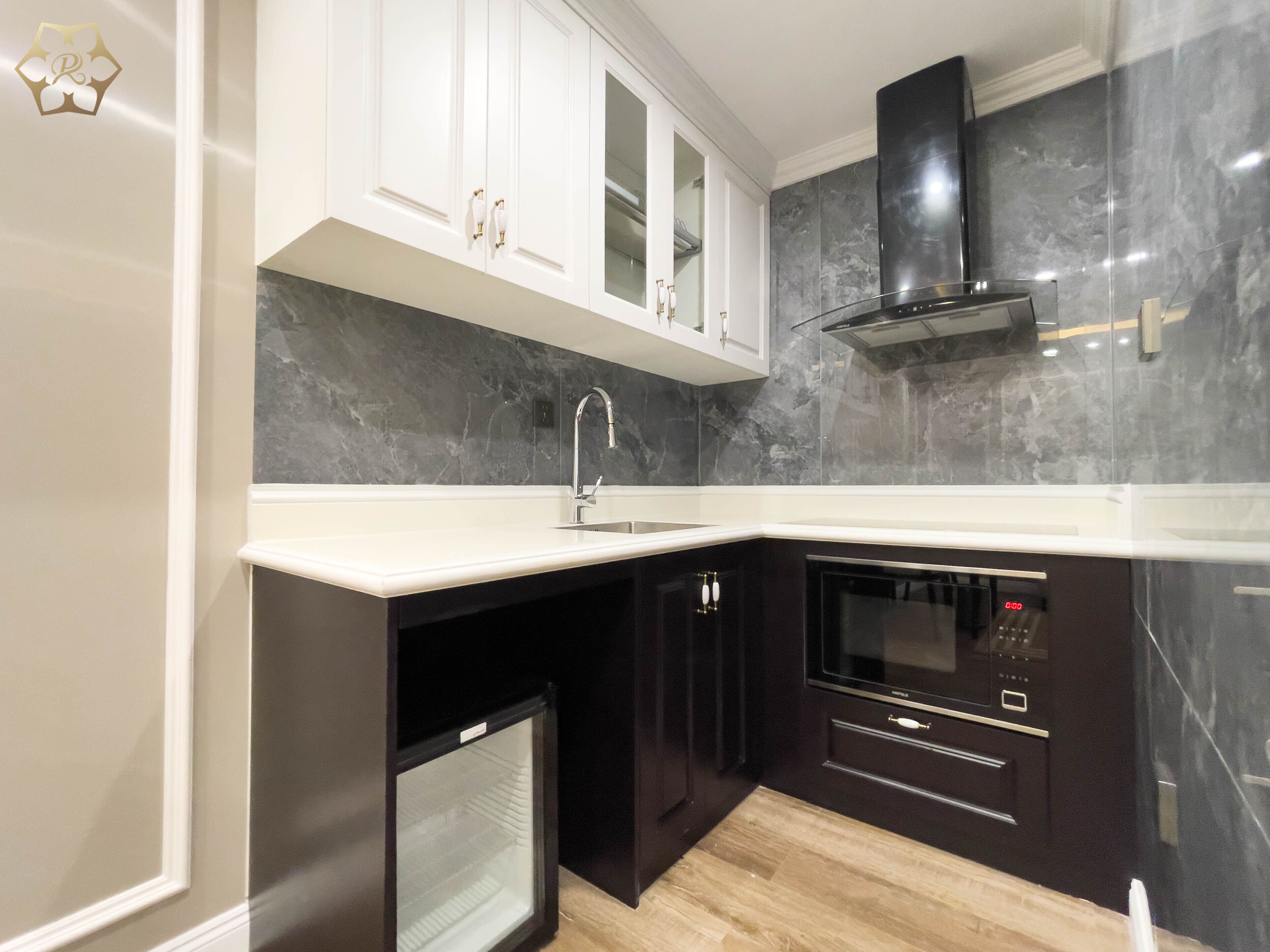 Cocina moderna con armarios blancos, horno negro y salpicadero de mármol.
