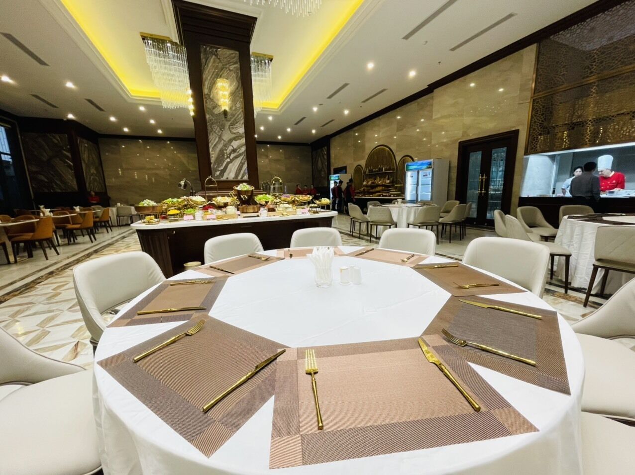A conference room with a round table set for a meeting, surrounded by white chairs.