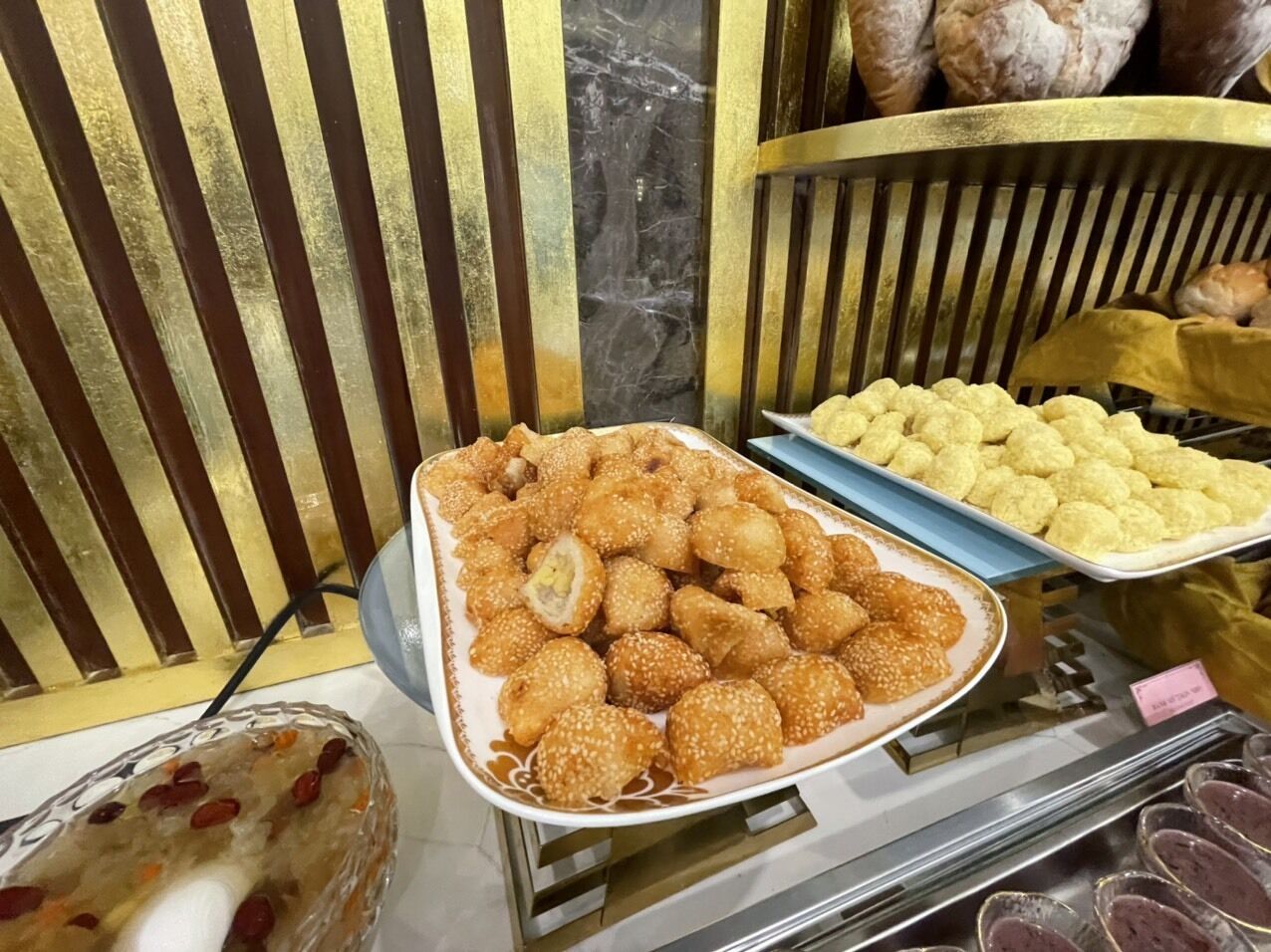 Una presentación de diversos aperitivos fritos, entre ellos productos empanizados y quizás algunas rosquillas, dispuestas en bandejas.