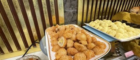 Una presentación de diversos aperitivos fritos, entre ellos productos empanizados y quizás algunas rosquillas, dispuestas en bandejas.