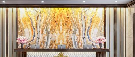 A reception desk with a marble wall backdrop, two computers, and a logo.