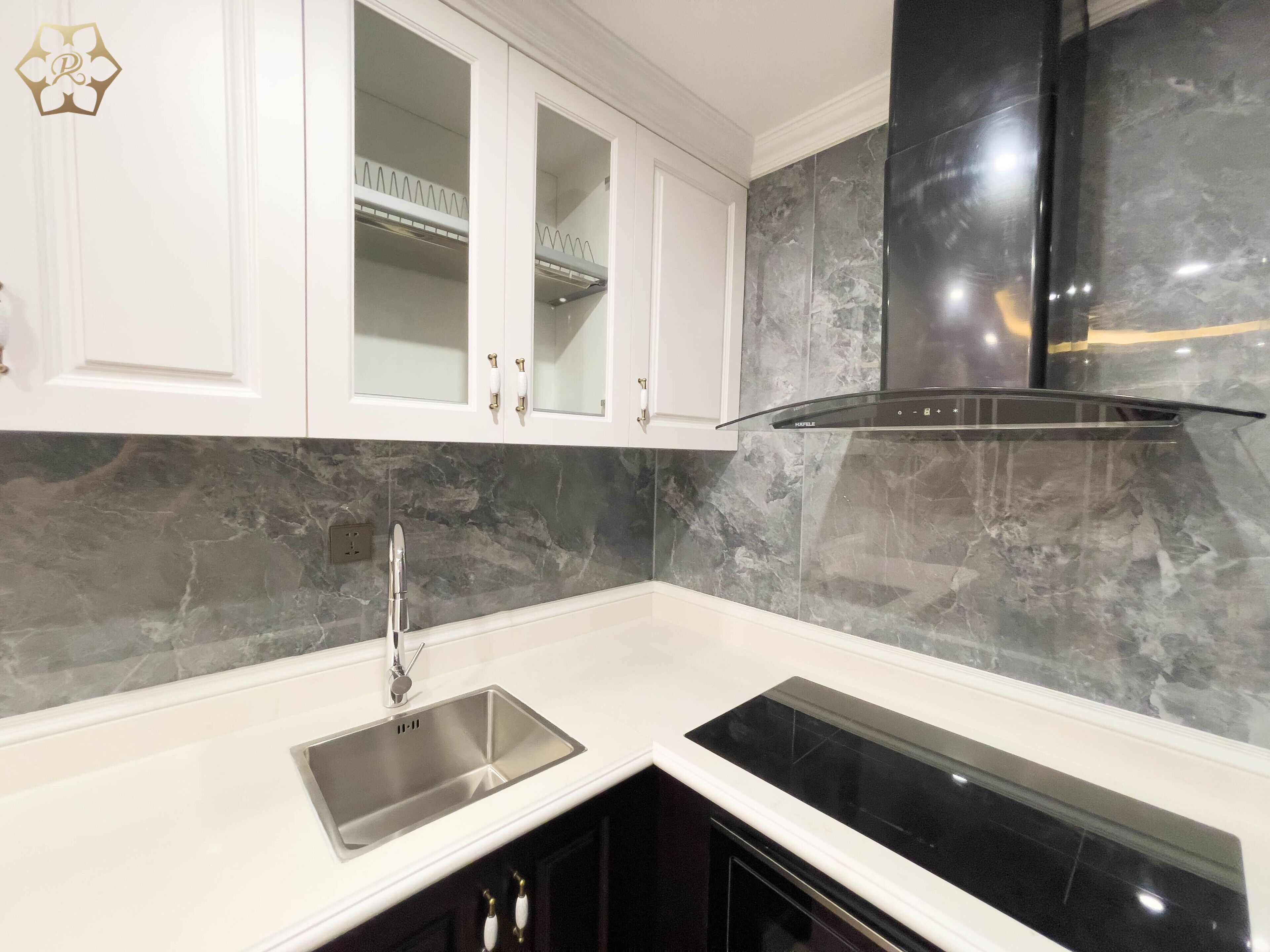 A modern kitchen with white cabinets, a stainless steel sink, and a black range hood.