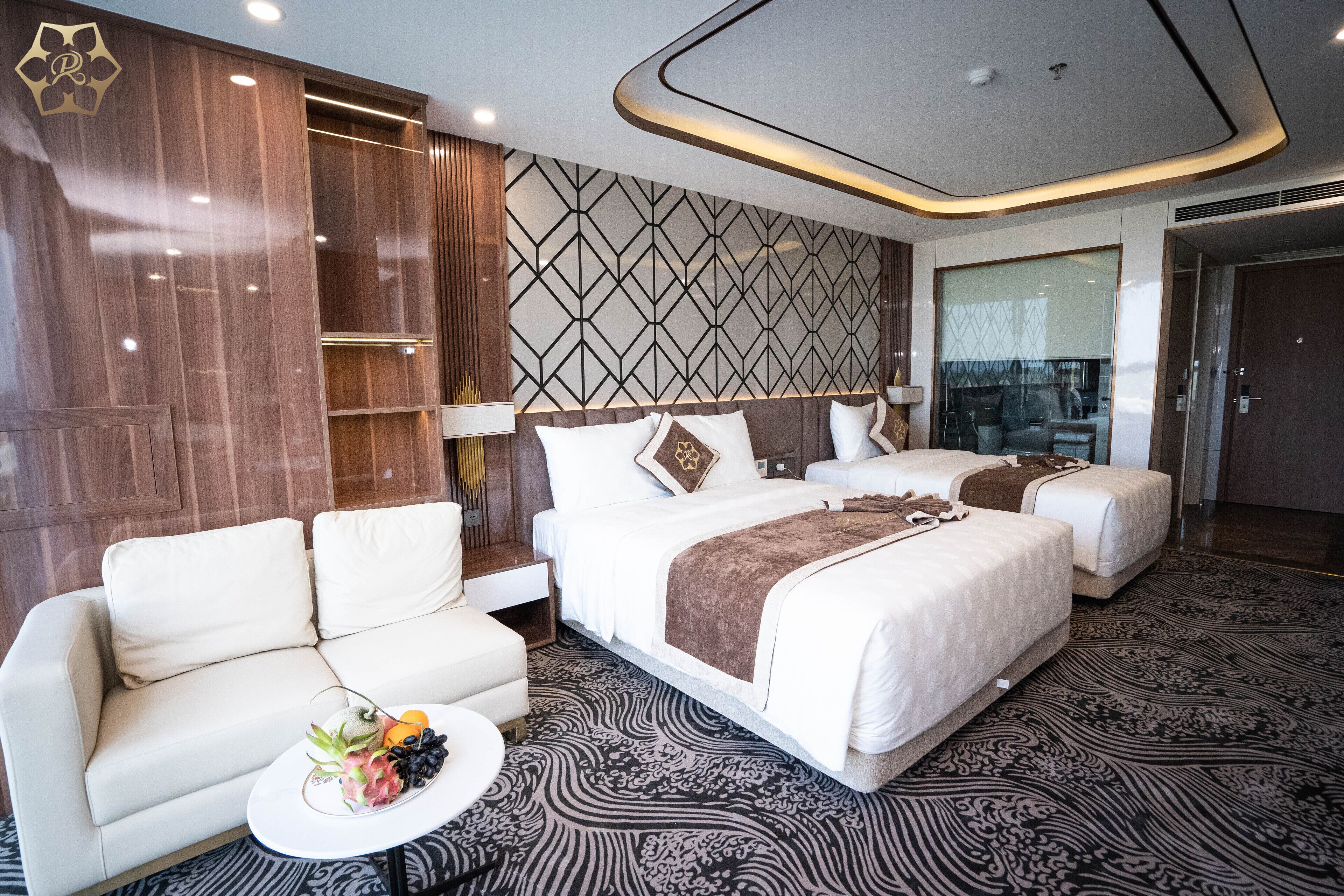 A hotel room with a large bed, two bedside tables, a sofa, and a decorative wall panel.