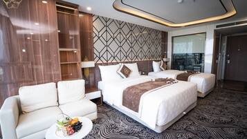A hotel room with a large bed, two bedside tables, a sofa, and a decorative wall panel.