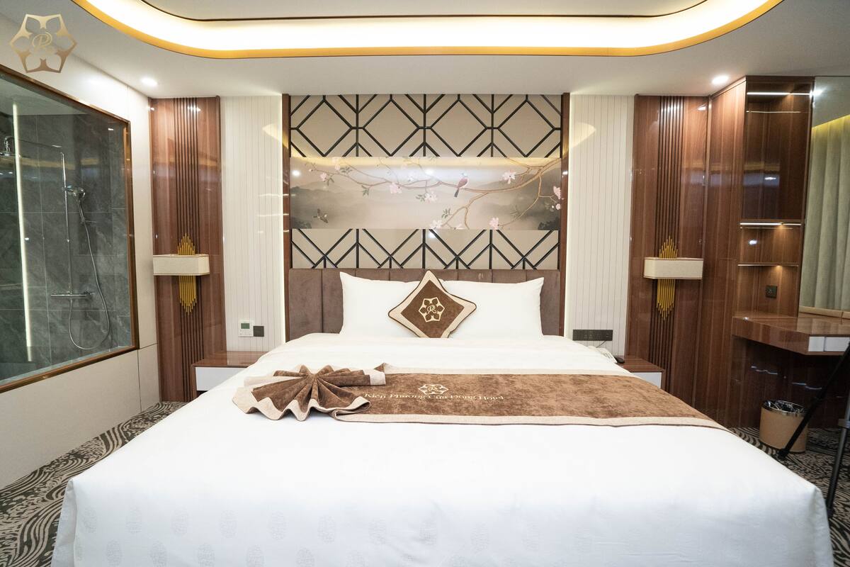 Une chambre d’hôtel avec un grand lit, une tête de lit en bois, une table de chevet et un miroir.