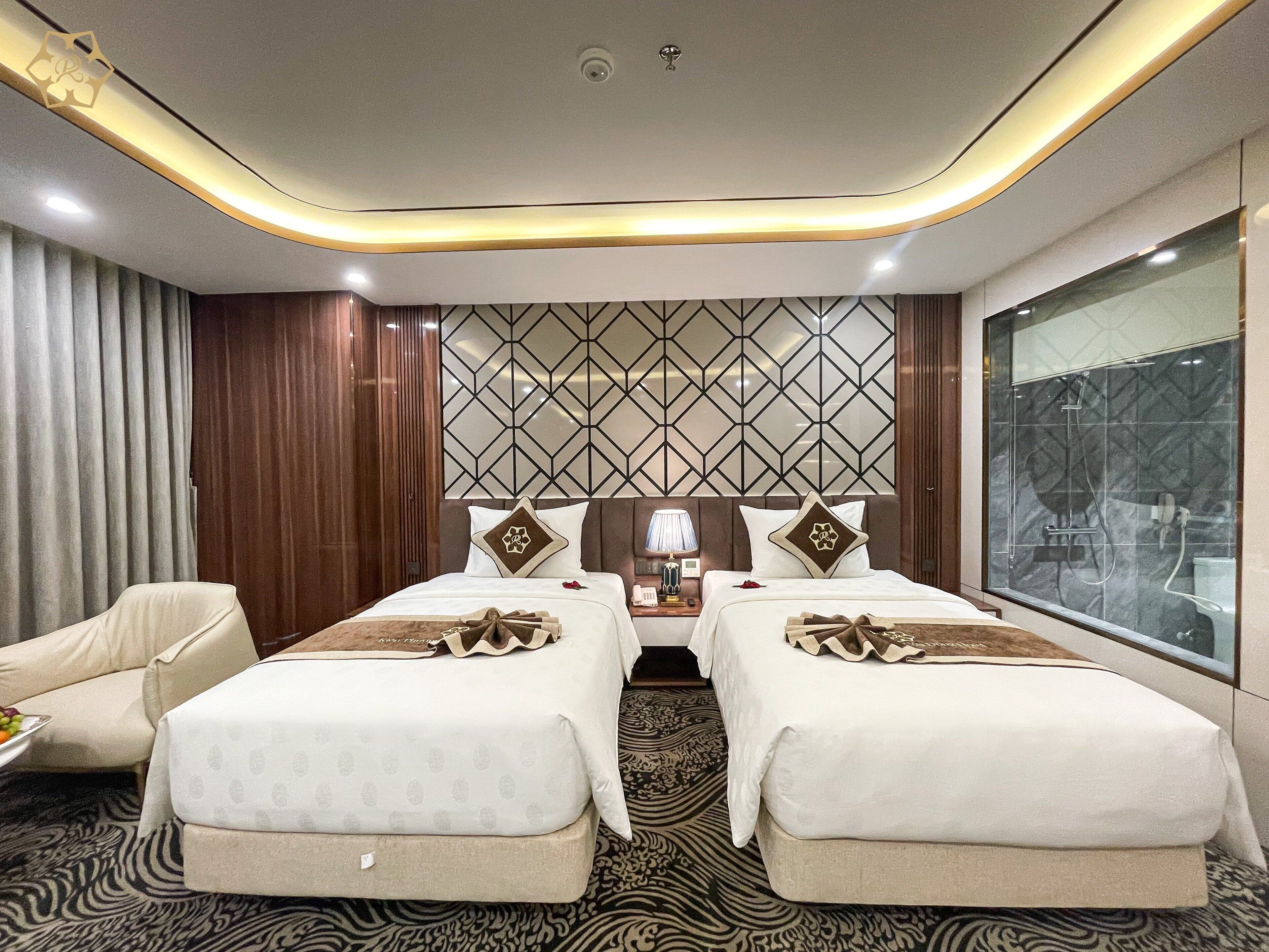 Une chambre d’hôtel avec deux lits, une grande fenêtre, un mur décoré de motifs et un plafond au design moderne.
