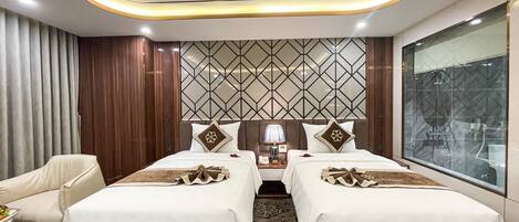 A hotel room with two beds, a large window, a patterned wall, and a modern ceiling design.