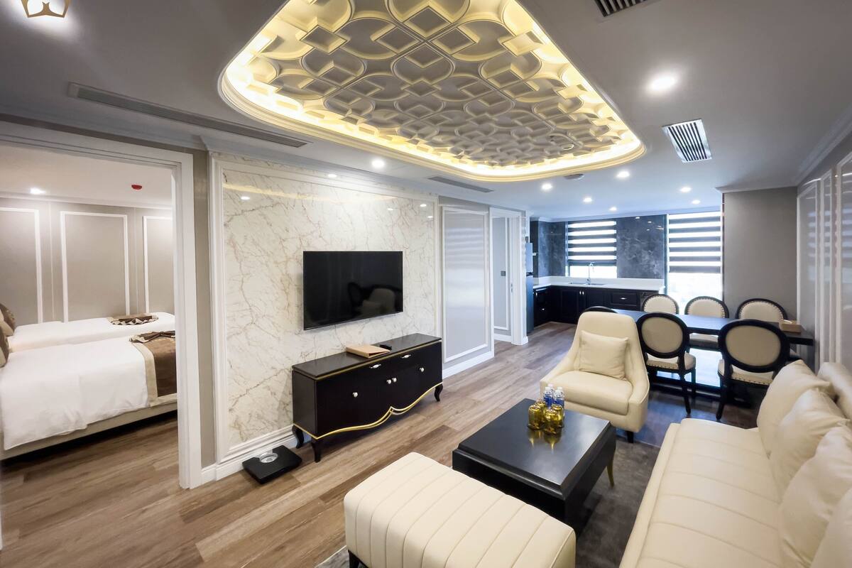 Une chambre d’hôtel moderne dotée d’un grand lit, d’une télévision, d’un coin repas avec des chaises et d’une cuisine.