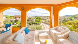 A balcony with a view of a residential area, furnished with wicker sofas and chairs, and a small table with a yellow vase. - Villa Ursula, 10 beds, 4 bedrooms, 4 bathrooms, sea view (San Teodoro)