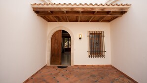A courtyard with a tiled floor, a wooden door, and a window with metal bars. - LLAMPUDOL (VILLA SA COMA) - Wonderful villa with private pool and free WiFi. (Sant Llorenç des Cardassar)