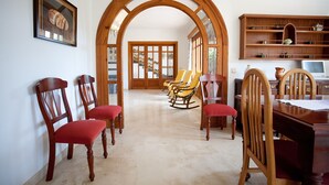 A dining area with wooden chairs, a dining table, and a wooden bookshelf. - LLAMPUDOL (VILLA SA COMA) - Wonderful villa with private pool and free WiFi. (Sant Llorenç des Cardassar)