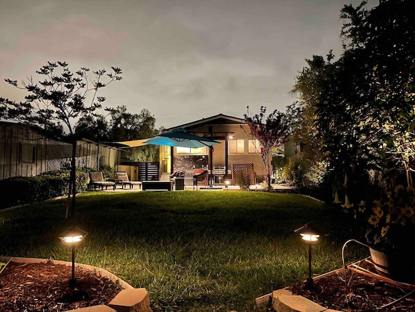 A residential backyard with a patio, outdoor furniture, and a house.