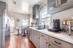 A modern kitchen with a stainless steel refrigerator, a double sink, and a coffee machine.
