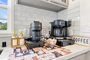 Une cuisine équipée de deux machines à café, d’une nappe à motifs de café et d’une enseigne sur le thème du café.