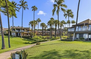 Un resort con edifici a più piani, palme e un prato curato.