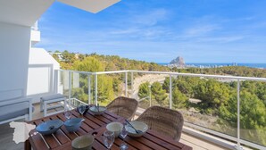 A balcony with a dining table set for four, overlooking a scenic landscape with trees and a distant city view. - CostaBlancaDreams - Real Ifach, El Gancho in Calpe (Calpe / Calp)