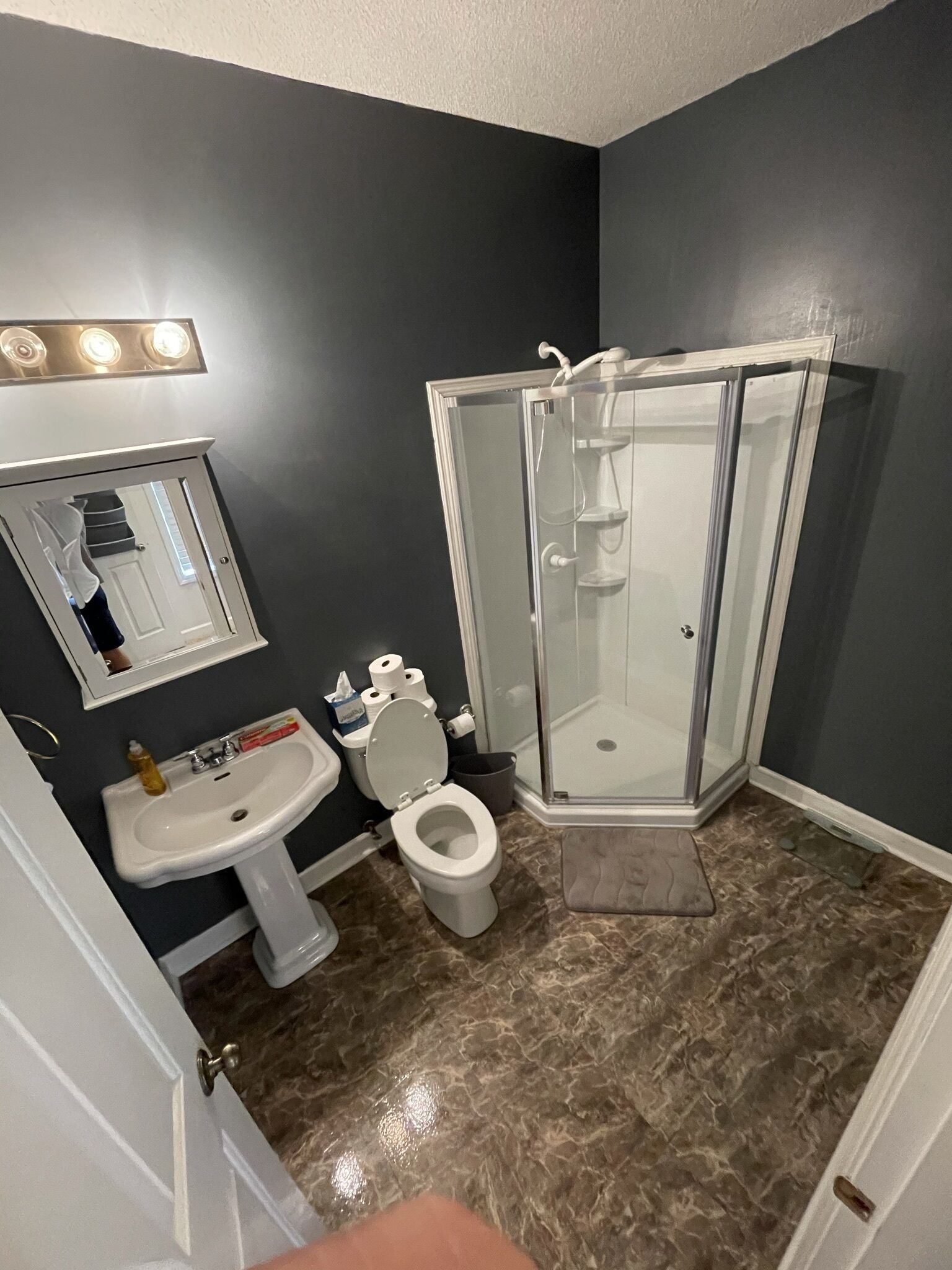 A bathroom with a white sink, toilet, and a glass-enclosed shower.