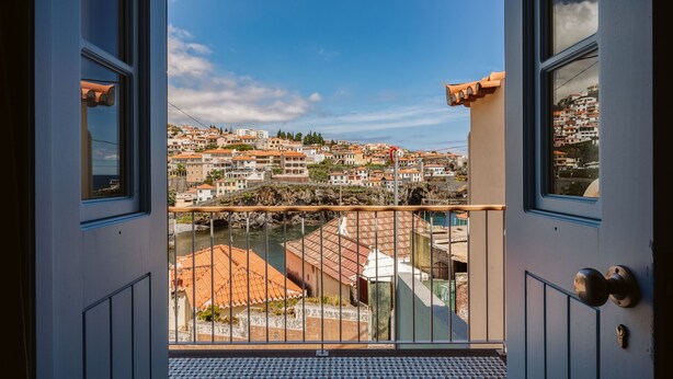 En balkon med udsigt over en kystby, der viser et område med terrassehuse og en flod.