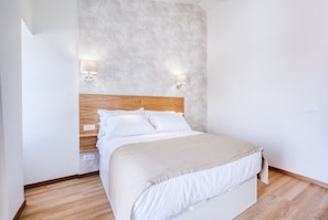 Une chambre à coucher avec une tête de lit en bois, deux lampes de chevet, un lit avec une literie blanche et un mur à motifs.