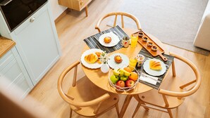 Et morgenbord med tallerkener med mad, en frugtkurv og en træbakke med kager.