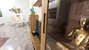 A modern living room with a wooden cabinet, a glass table, and a Buddha statue. - RentalSevilla 3 bedroom apartment in Triana (Sevilla)