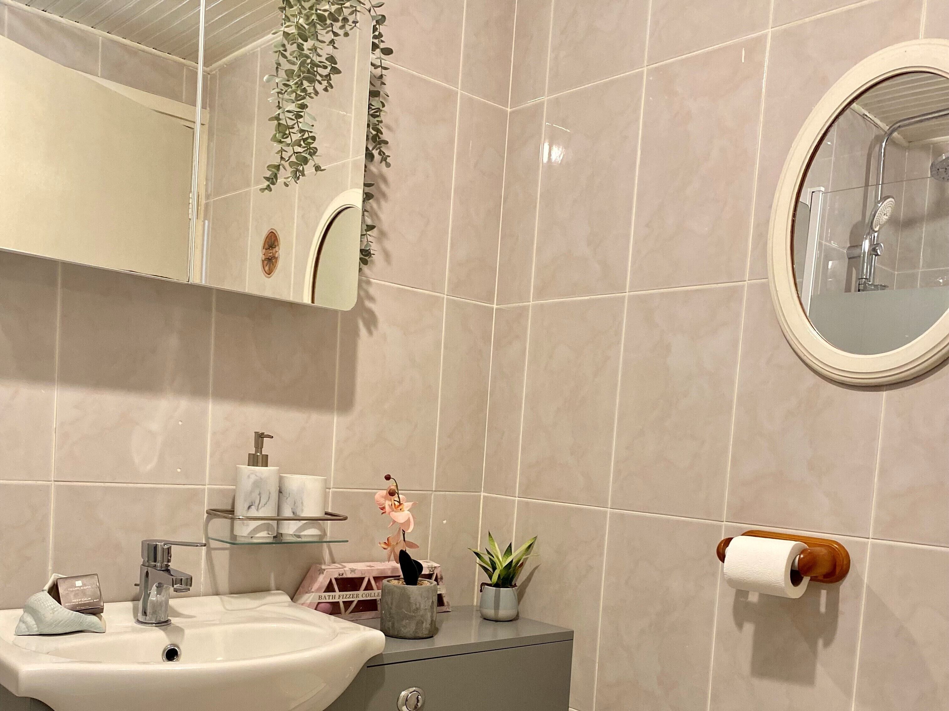 A bathroom with a sink, mirror, and shower.