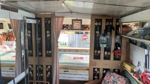 A room with a wooden door, a mirror, a small table with a vase, and a shelf with various items. - 2 x Double Bed Glamping Wagon at Dalby Forest (Scarborough)