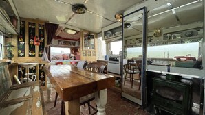 A compact kitchen with a wooden table, a stove, and a window overlooking a scenic view. - 2 x Double Bed Glamping Wagon at Dalby Forest (Scarborough)