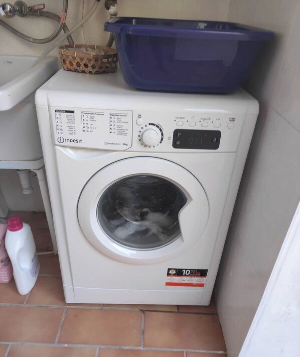 Une machine à laver compacte dotée d’un écran numérique, d’un panneau de commande et d’un panier situé sur le dessus.